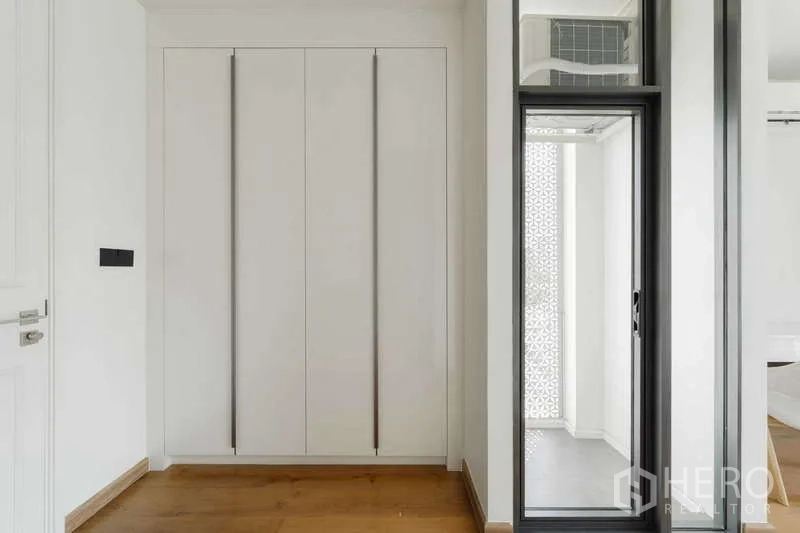 Townhouse for rent or sale in Watthana, Bangkok - Hallway with built-in wardrobe and a sliding glass door to a small balcony.
