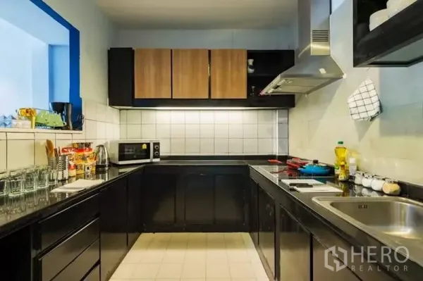 Townhouse for rent in Watthana, Bangkok - U-shaped kitchen with black cabinets, tiled backsplash and range hood.