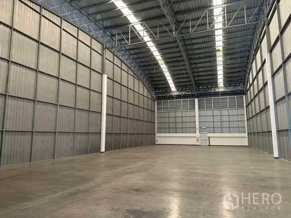 Factory for rent in Bang Sao Thong, Samut Prakan - Spacious warehouse interior with high metal walls, skylight strips and polished concrete floor.