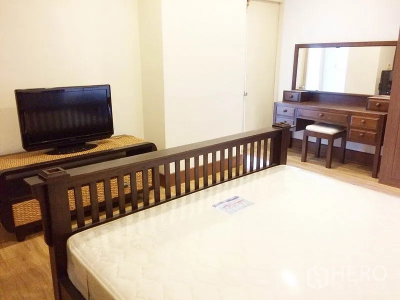 Condominium for rent in Khlong Toei, Bangkok - Cozy bedroom angle showing bed, TV console and dressing table.