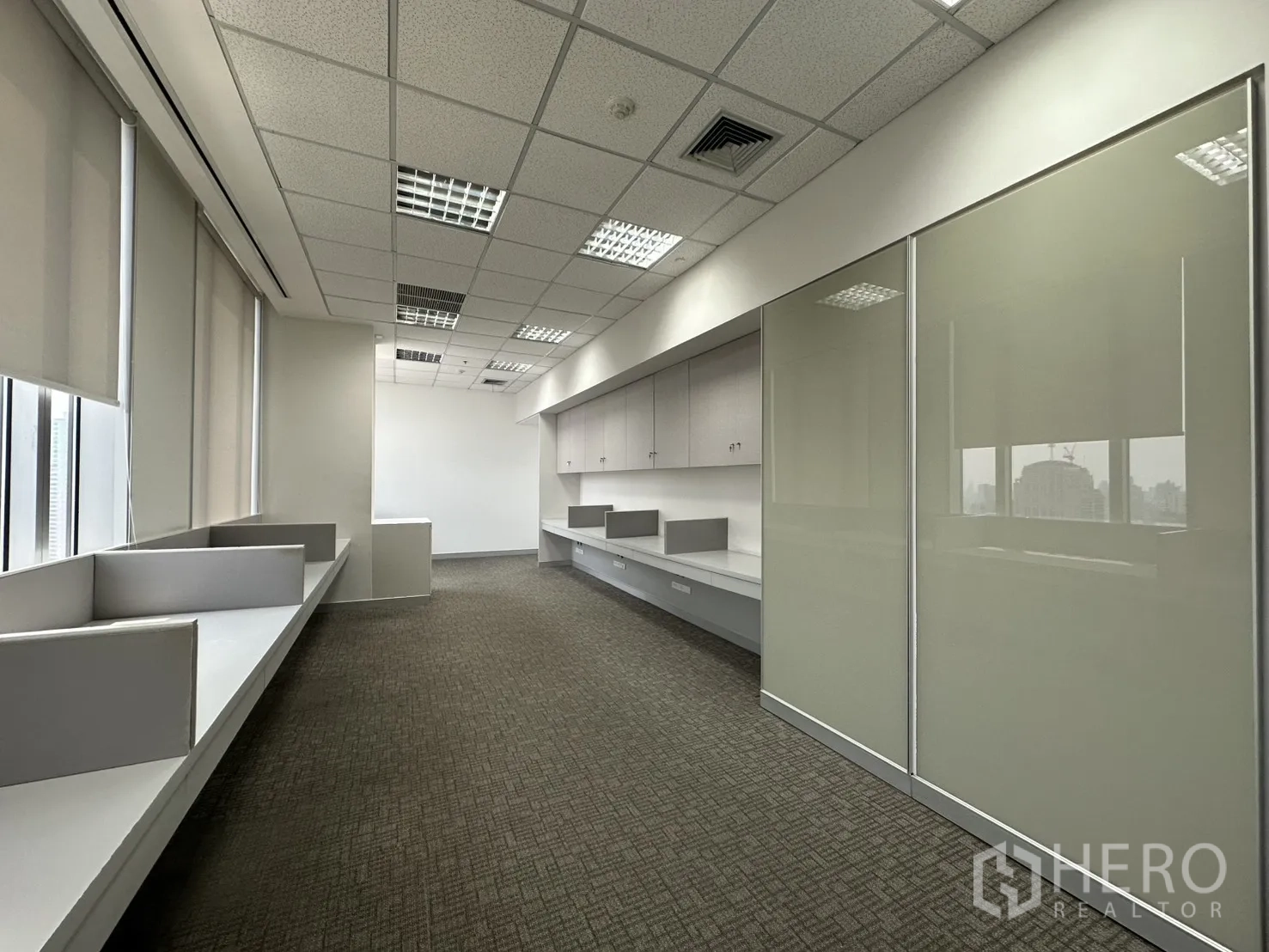 Office Space for rent in Khlong Toei, Bangkok - Open-plan office area with built-in workstations, cabinets, and window blinds.