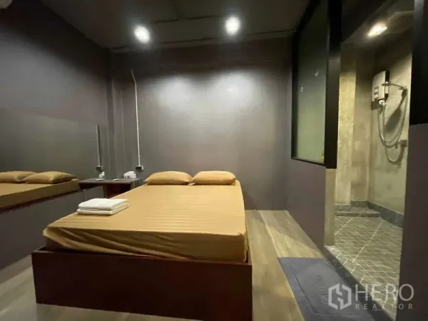 Shophouse for rent in Lat Phrao, Bangkok - Compact bedroom with platform bed, wood floor and ensuite shower in gray tones.
