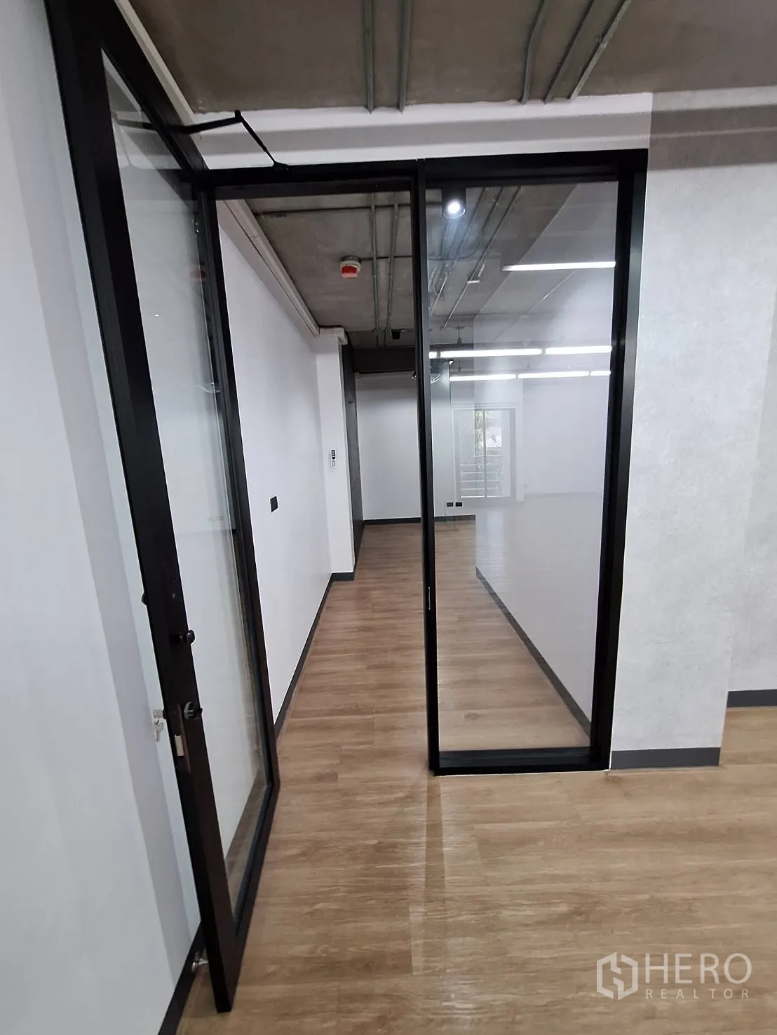 Office Space for rent - Private room with industrial pendant lights, window and wood-look flooring.
