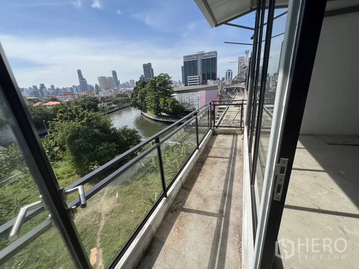 Shophouse for sale in Suan Luang, Bangkok - Narrow balcony with glass railing overlooking a canal and Bangkok skyline.
