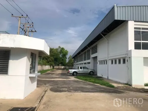 Factory for rent or sale in Bang Pa-in, Phra Nakhon Si Ayutthaya - Entrance driveway with security booth, parking area and side elevation of the factory.