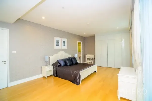Condominium for rent in Khlong Toei, Bangkok - Spacious master bedroom with king bed, wood flooring, built-in wardrobes and a door to the ensuite bathroom.