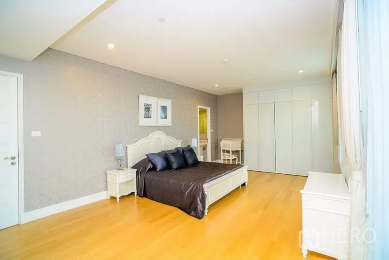 Condominium for rent in Khlong Toei, Bangkok - Spacious master bedroom with king bed, wood flooring, built-in wardrobes and a door to the ensuite bathroom.