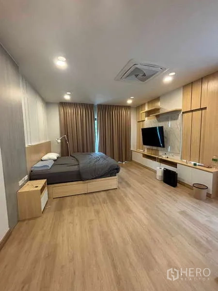 Detached House for rent in Mueang Nonthaburi, Nonthaburi - Master bedroom with warm wood floors, TV wall, built-in shelves and king bed.