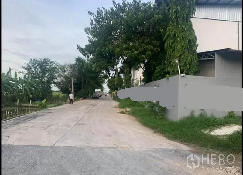 货栈 出租在Sai Noi, Nonthaburi - 通往仓库的安静道路，旁有运河与树木
