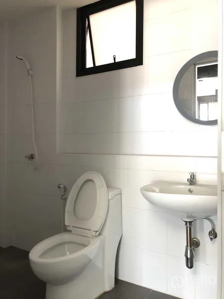 Warehouse for rent in Bang Phli, Samut Prakan - Clean white bathroom with toilet, round mirror, sink and shower.