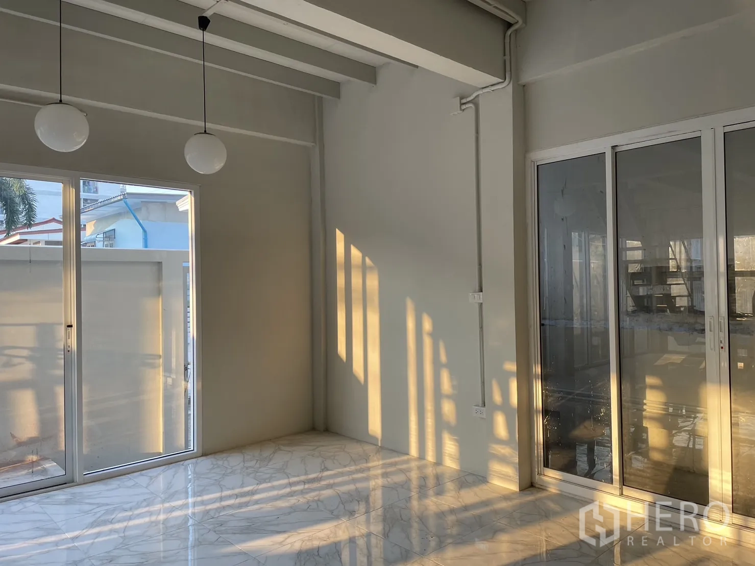 Detached House for rent or sale in Din Daeng, Bangkok - Sunlit lounge with sliding doors on two sides and polished marble-look tiles.