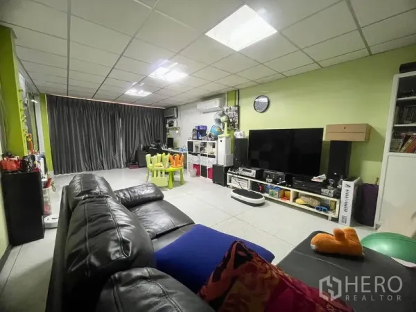Townhouse for rent in Sathon, Bangkok - Spacious living room with black leather sofa, large TV wall and kids play corner.