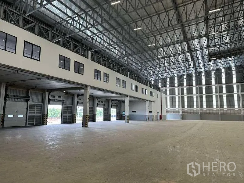 Factory for rent or sale in Samut Prakan - Warehouse interior showing dock-high doors and steel roof structure.