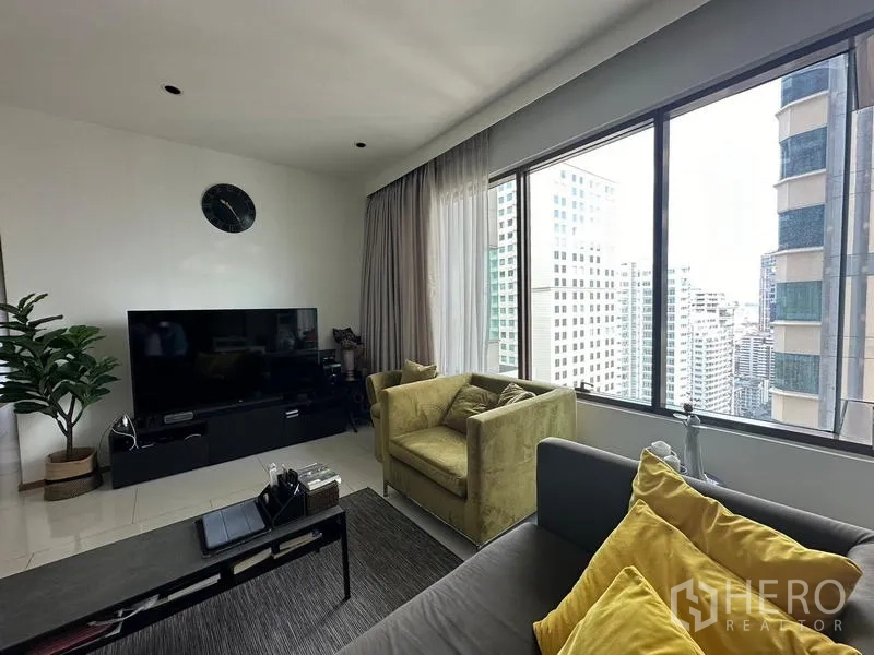 Condominium for sale in Khlong Toei, Bangkok - Lounge seating by panoramic windows overlooking the Bangkok skyline.