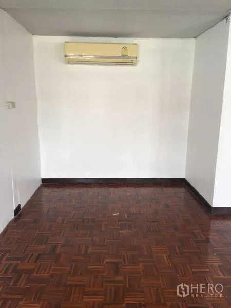 Townhouse for rent in Phra Khanong, Bangkok - Compact room with wall-mounted air conditioner and parquet floor.