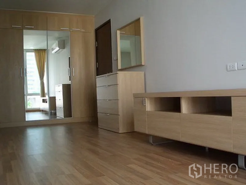 Apartment for rent in Khlong Toei, Bangkok - Bedroom featuring built-in mirrored wardrobe, dresser and light wood flooring.