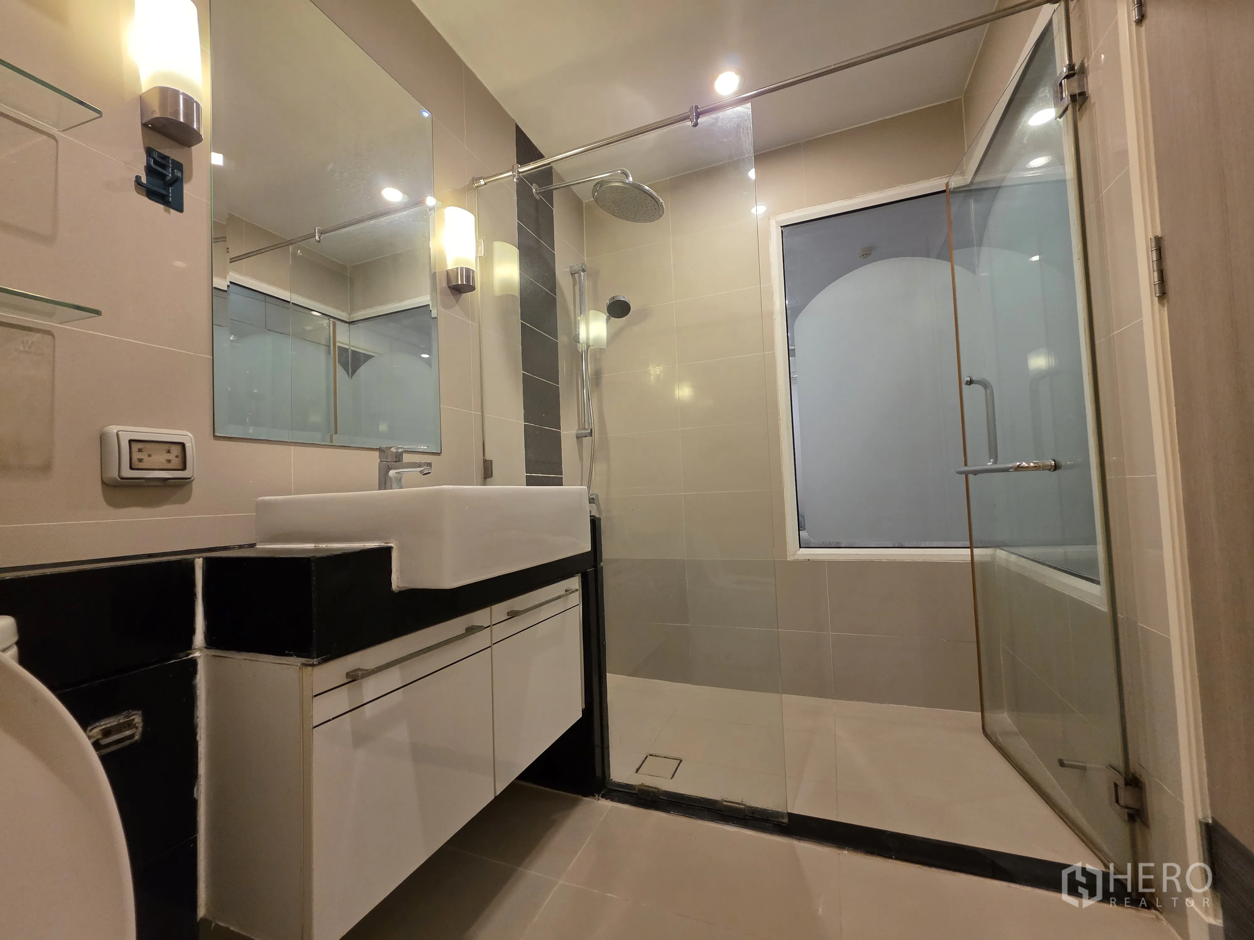 Condominium for rent in Bang Kapi, Bangkok - Bathroom with glass-enclosed rain shower and wide vanity mirror.