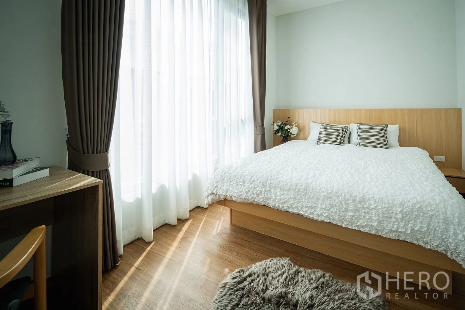 Townhouse for rent in Bang Phli, Samut Prakan - Primary bedroom with king bed, floor-to-ceiling curtains and wood flooring.