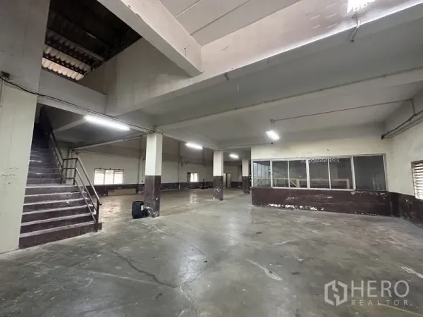 Factory for rent in Bang Bua Thong, Nonthaburi - Ground-floor warehouse hall with concrete floor, columns, and glass-partition office.