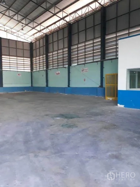 Factory for rent in Samut Prakan - Open production area with high ceilings, internal office box, and level concrete floor.