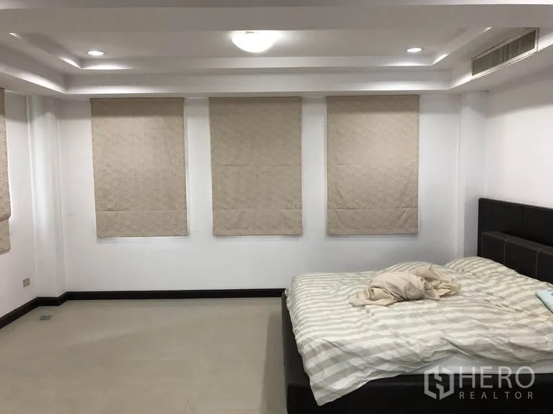 Home Office for rent in Wang Thonglang, Bangkok - Large bedroom with tray ceiling, light-colored blinds and a queen-size bed.