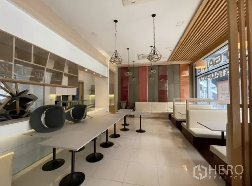 Retail Space for rent in Khlong Toei, Bangkok - Modern café-style retail interior with booth seating, pendant lights, and long tables on glossy tile flooring.