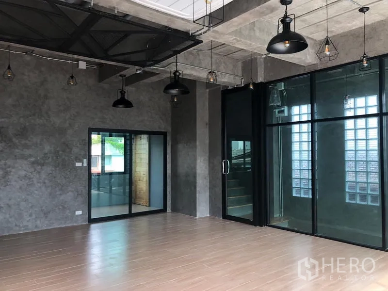带办公室的家 出租在Suan Luang, Bangkok - 工业风工作室，清水混凝土墙、吊灯和推拉玻璃门。