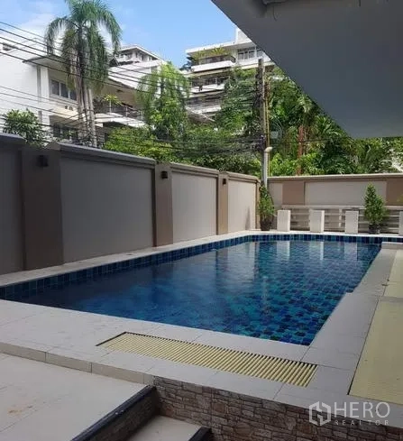 Apartment for rent in Khlong Toei, Bangkok - Outdoor communal swimming pool with blue mosaic tiles and privacy walls around.