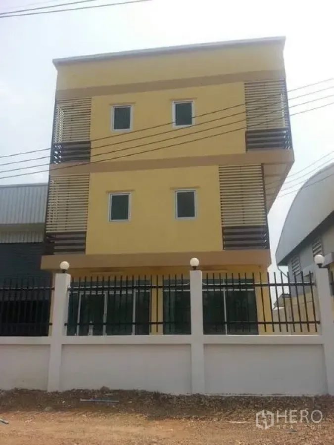 โรงงาน ให้เช่าหรือขายในKhlong Luang, Pathum Thani - อาคารสำนักงาน 3 ชั้นสีเหลืองพร้อมระแนงและรั้วหน้า ภายในโครงการโรงงานที่คลองหลวง