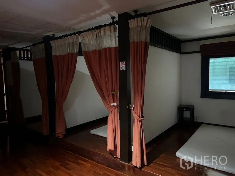 Shophouse for rent in Phra Khanong, Bangkok - Private Thai massage area with floor mattresses, peach curtains and raised wooden platform.
