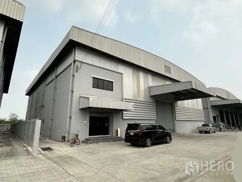 Warehouse for rent in Bang Phli, Samut Prakan - Modern grey warehouse exterior with metal cladding, loading bay canopies and a wide concrete yard in Bang Phli.