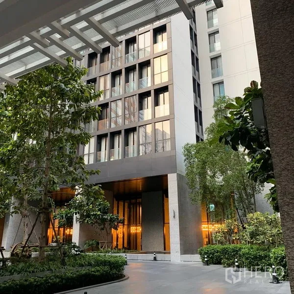 Condominium for rent in Pathum Wan, Bangkok - Modern condominium entrance with landscaped courtyard and tall facade in Pathum Wan.