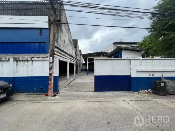 Warehouse for rent in Phra Khanong, Bangkok - Warehouse entrance gate opening to a concrete driveway and loading yard.