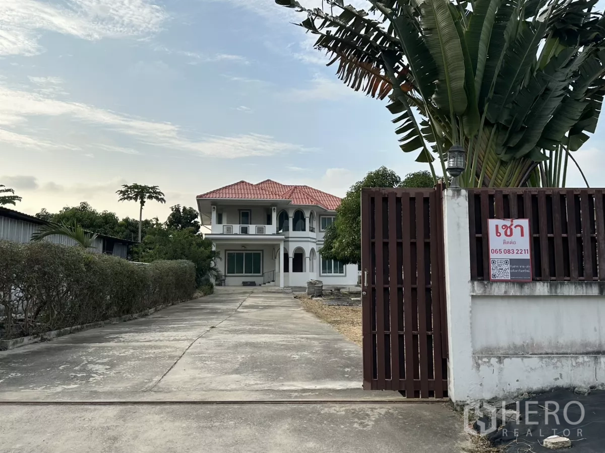 Home Office for rent - Gated entrance with long driveway leading to a two-storey white home office and large yard.