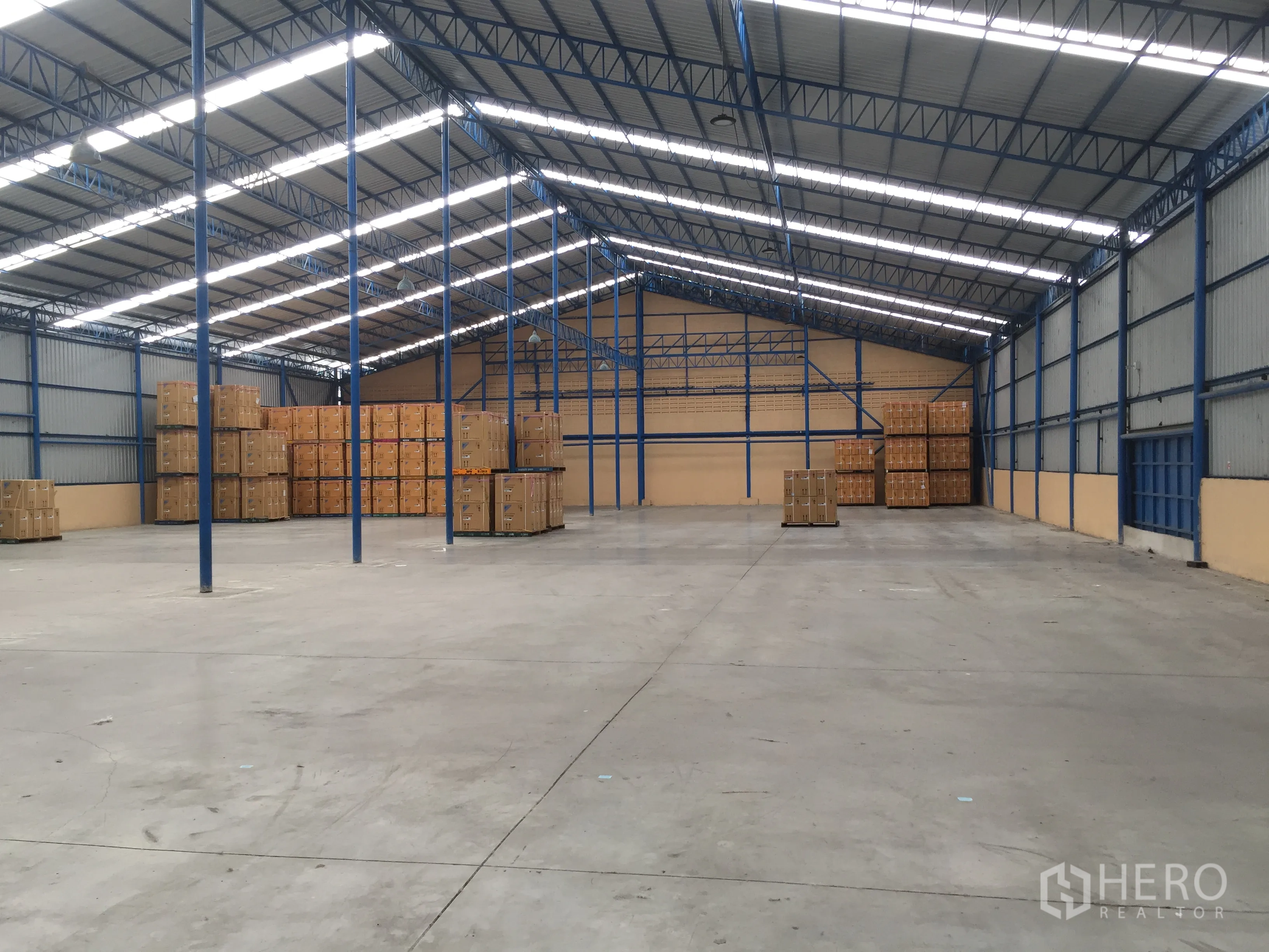 Warehouse for rent in Lat Krabang, Bangkok - Open warehouse floor with stacked cartons, high clear height, steel trusses, skylights and multiple loading bays.