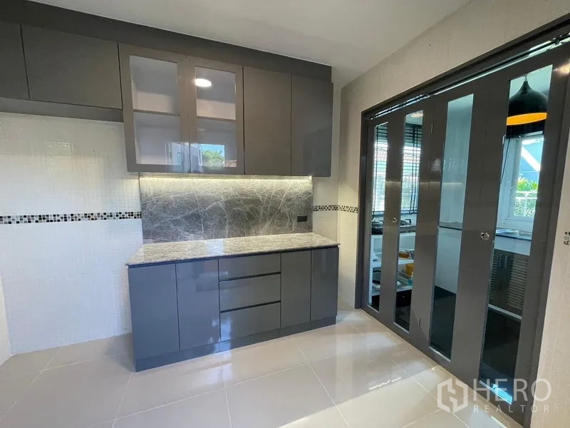 Detached House for sale in Lam Luk Ka, Pathum Thani - Kitchen with backlit stone backsplash and glass sliding partition to the cooking area.