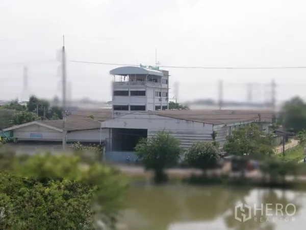 Warehouse for rent in Pathum Thani - Aerial view of a multi-building warehouse complex beside a canal with greenery in Pathum Thani.
