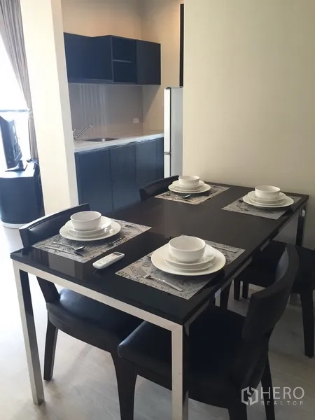Condominium for rent in Khlong Toei, Bangkok - Dining area set for four beside the open kitchenette, creating a practical space for meals.