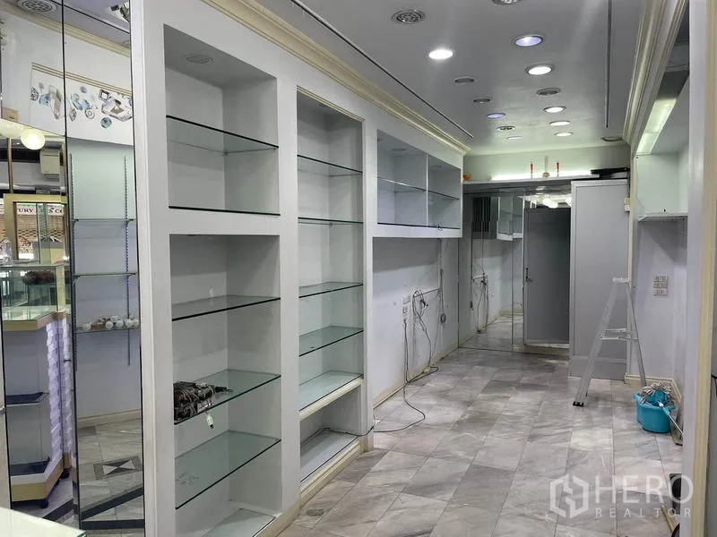 Shophouse for rent in Bang Rak, Bangkok - Mirrored wall and continuous glass shelving running the length of the shop.