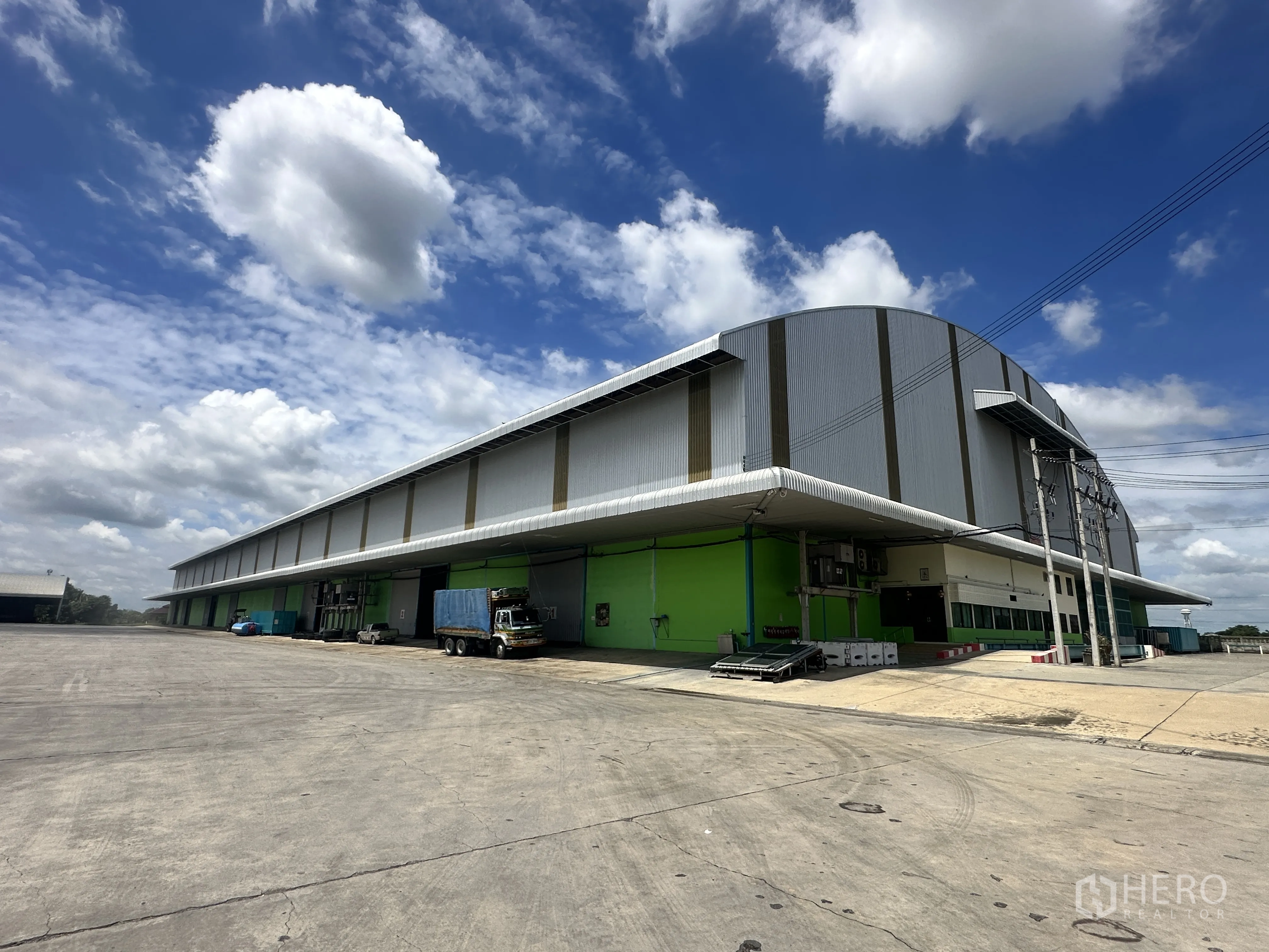 โกดัง for rent in Sai Noi, Nonthaburi - ภาพมุมเอียงของอาคารโกดังขนาดใหญ่ พร้อมลานกว้างสำหรับรถบรรทุกหมุนตัว