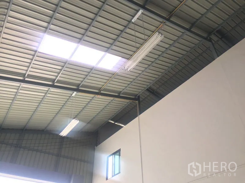 Warehouse for sale in Khlong Luang, Pathum Thani - Steel roof with skylight panels and fluorescent lighting fixtures.
