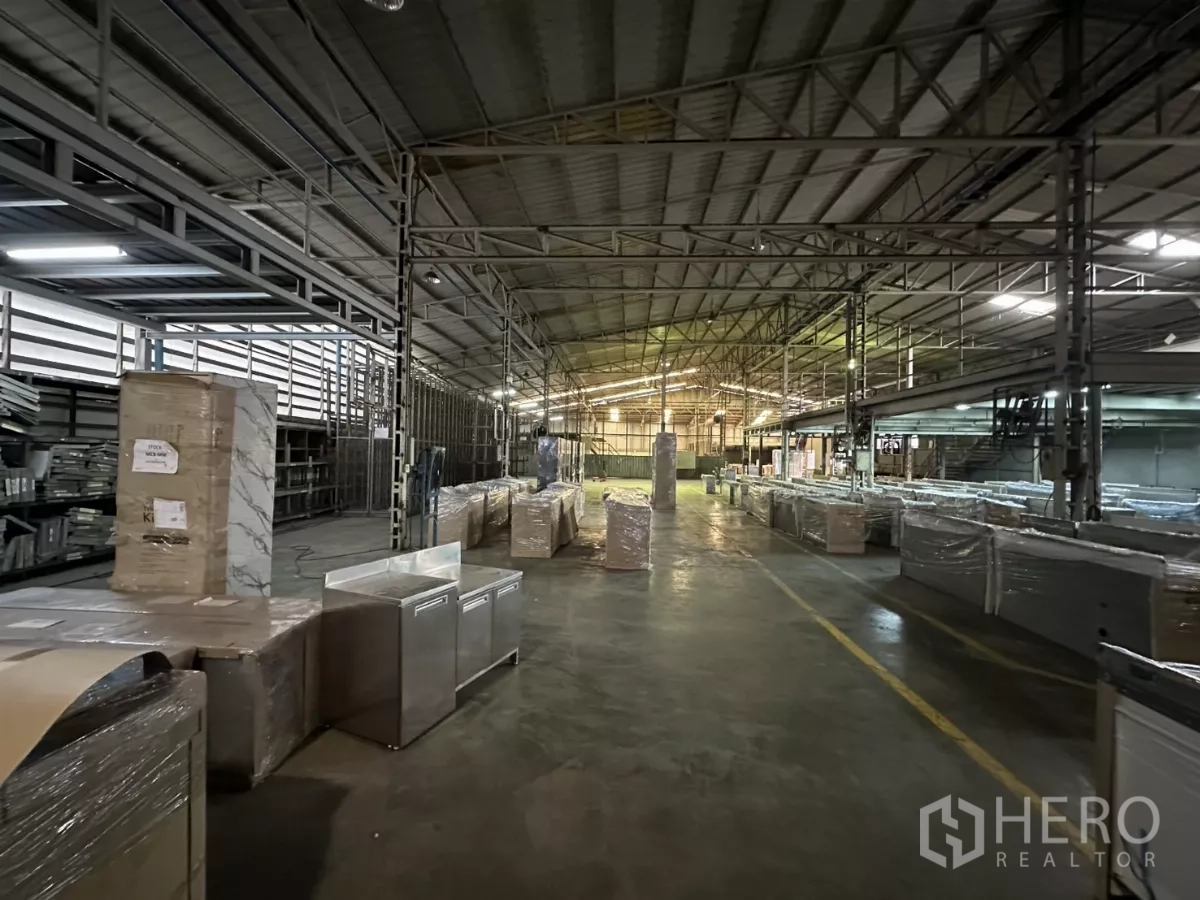 Warehouse for rent in Yan Nawa, Bangkok - Storage zone with wrapped goods and a central lane for forklifts.