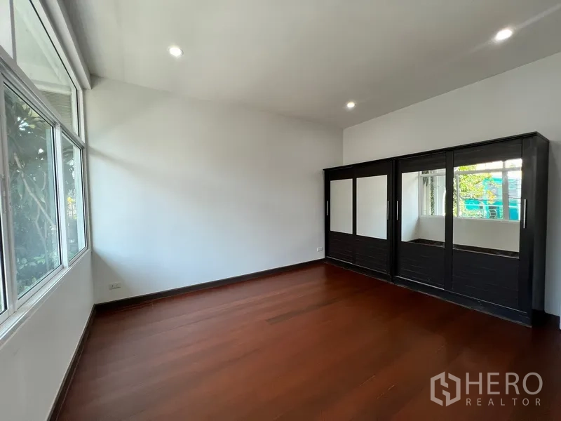 Home Office for rent in Watthana, Bangkok - Spacious bedroom with polished wood flooring and a large wardrobe.