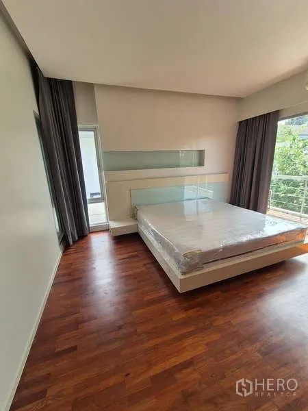 Detached House for rent in Bang Kruai, Nonthaburi - Spacious bedroom with built-in headboard, large windows and balcony access.