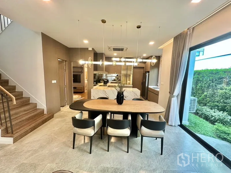 Detached House for rent in Samut Prakan - Dining area beside sliding doors to the garden, connected to a modern kitchen.