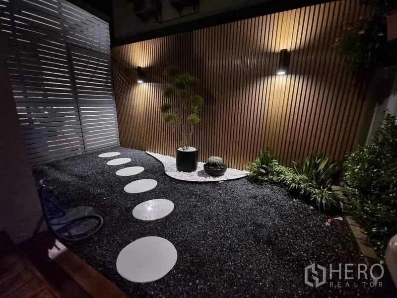 Detached House for sale in Khan Na Yao, Bangkok - Night view of a zen-style garden with pebble ground, stepping stones and slatted wall lights.