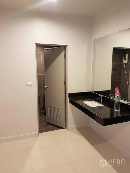Shophouse for rent or sale in Bang Na, Bangkok - Bathroom vanity with black stone countertop, under-mount sink and large mirror.