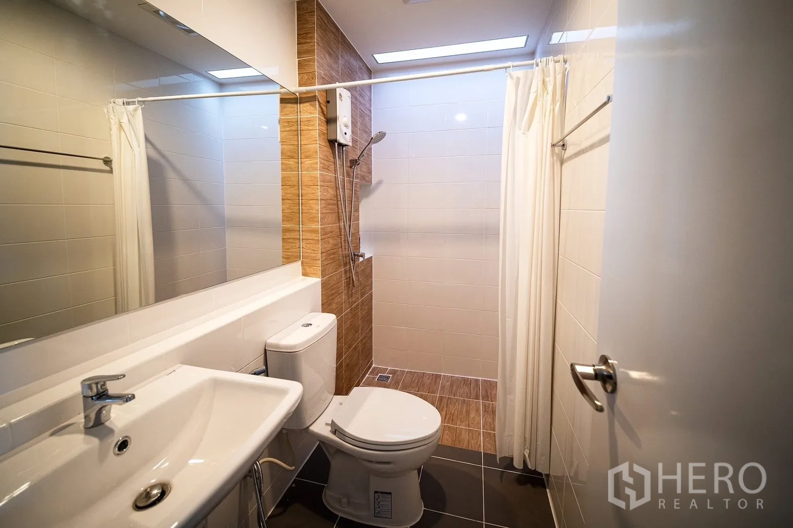 Townhouse for rent in Bang Phli, Samut Prakan - Second bathroom featuring a shower area with curtain and a long vanity mirror.