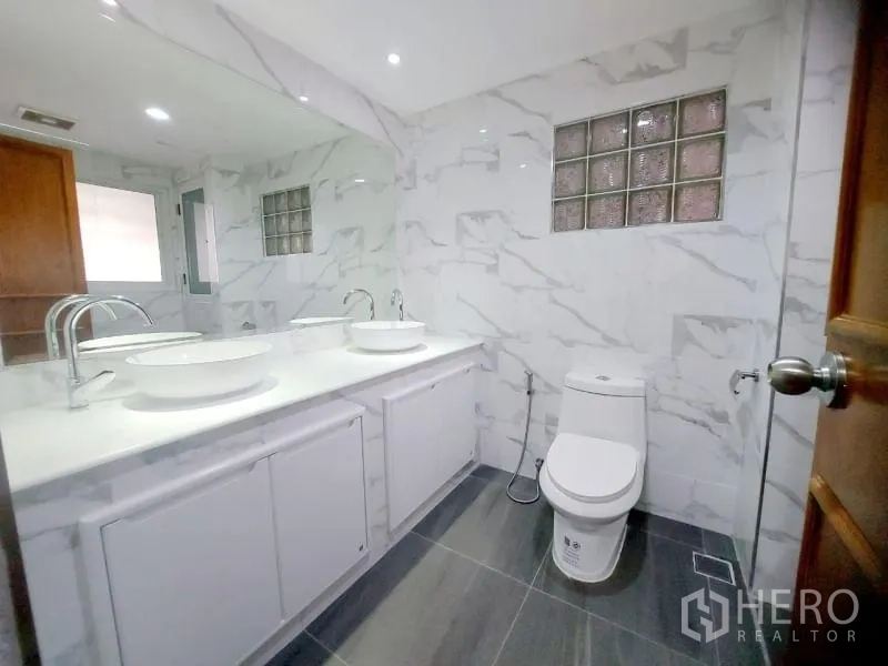 Condominium for rent in Watthana, Bangkok - Second bathroom with twin basins, marble-style walls and toilet next to the shower area.