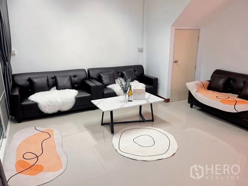 Townhouse for rent in Huai Khwang, Bangkok - Seating zone with three sofas, modern rugs and a central coffee table.